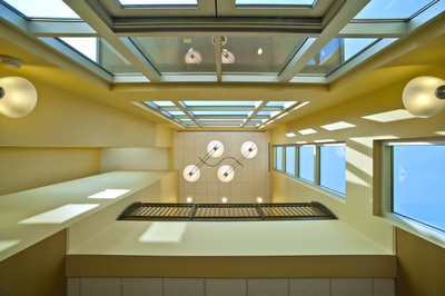 ground view up of stairwell area showcasing geometric light fixtures, open vertical windows