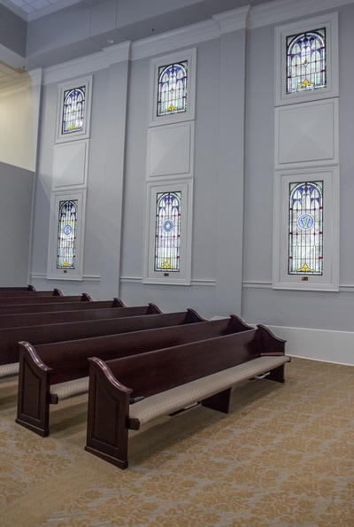 side view of First Baptist Church of Waynesboro showing pews and rectangular stained glass windows on white wall 