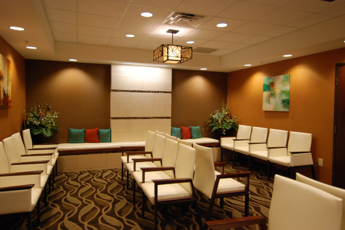 waiting room of Women's Health of Augusta featuring rich neutral tones in carpeting and wall color with pops of red and green