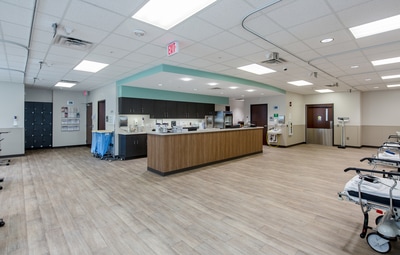 nurse's station in Augusta Endoscopy Center with mint green accents, dark wooden cabinetry and mid toned wood paneling around the station itself