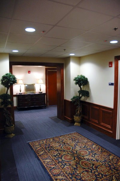 dark wooden stained paneling and decorative ficus trees on navy carpeting in hallway of Lewis Hall at Georgia Southern University 