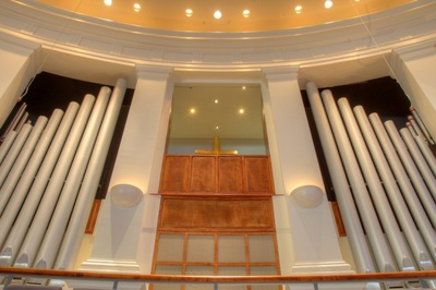 view up of organ and crucifix on wood paneling behind pulpit of First Baptist Church of North Augusta 