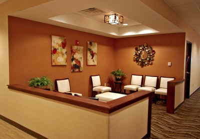 secondary waiting room of Women's Health of Augusta with warm neutral toned walls and carpeting and pops of red and green