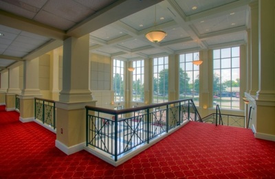red carpeted staircase and hallway overlooking open front entrance and large front view windows of Curtis Baptist Church and School 