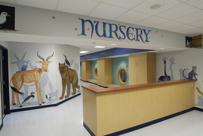 front desk leading into nursery with painted animals on wall 