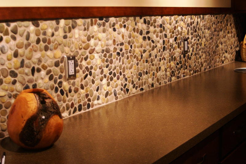 counterspace with neutral pebble motif backsplash and decorative brown toned vase