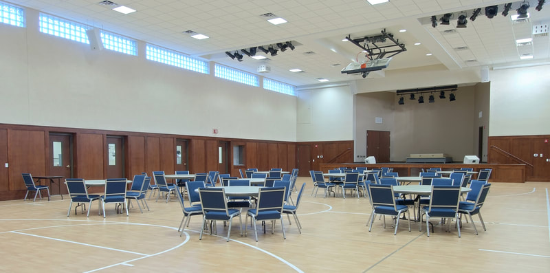 multipurpose space with chairs and tables facing a stage