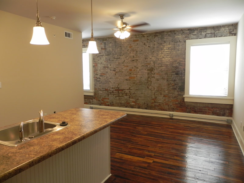 Stone accent wall and large windows with view of brown tonal granite island and sink 