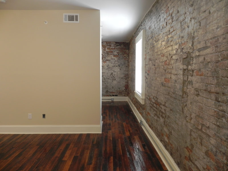 interior of Lowrey Wagon Works Apartments unit with stone accent wall and glossy wood flooring 