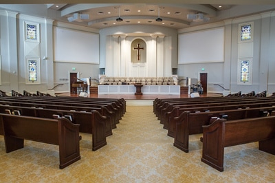 front view of sanctuary leading to pulpit with wooden pews and golden patterned carpeting 