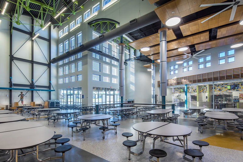 large open floor plan cafeteria seating in Butler High School with large windows, high ceilings, neon green decorative accents on ceiling