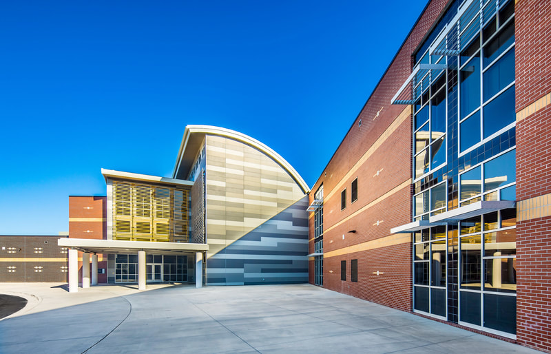 Exterior of geometric building housing Butler high school done in shades of grey stucco and red brick 