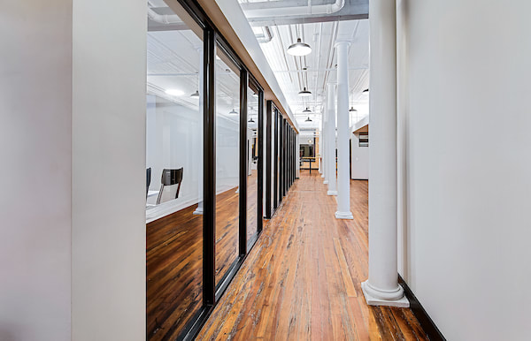 open hallway leading to conference rooms with decorative white poles and rich wooden flooring