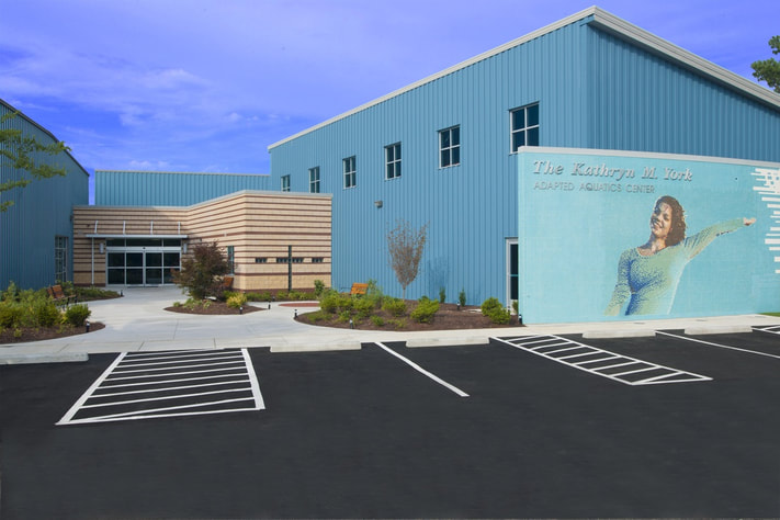 Large blue building housing the Kathryn M. York Adapted Aquatic Center with tile mosaic mural of Kathryn 
