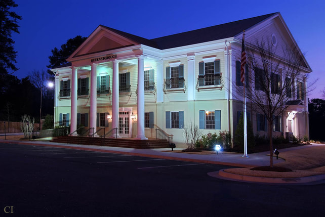 night time exterior shot of two story yellow Queensborough National bank in Augusta