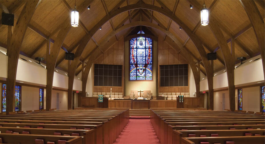 interior of sanctuary of Aldersgate UMC with large stained glass window above alter
