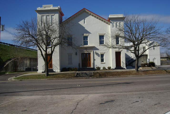 Front view of stucco St. Luke United Methodist Church building in winter with clear sky and barren trees