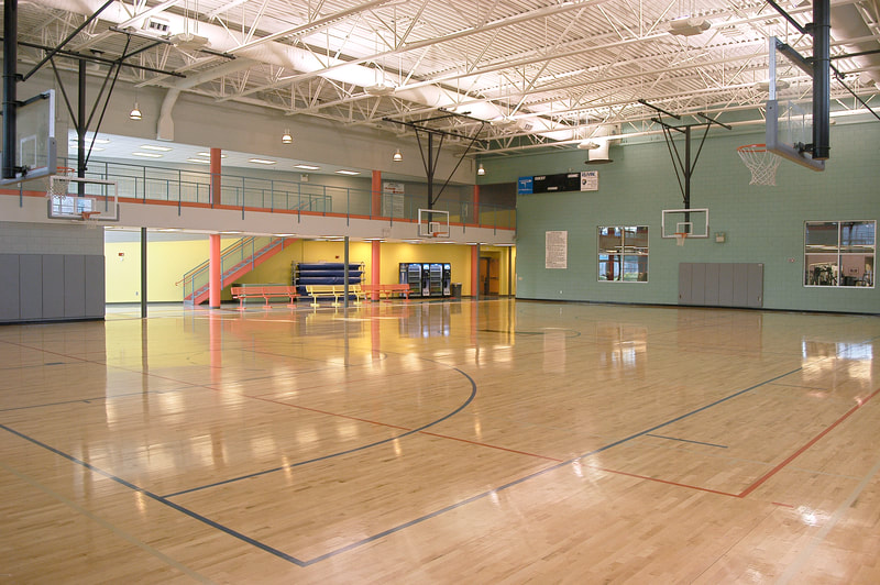 Augusta Family Y multi purpose regulation sized gymnasium with basketball hoops and an open air second floor hallway 
