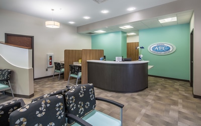 front reception area of Augusta Endoscopy Center with wood paneled privacy partitions, facing a mint green accent wall with company logo