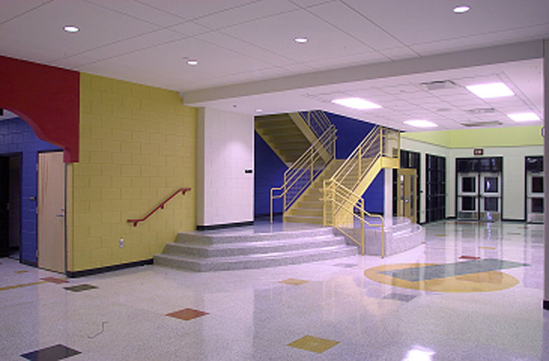 colorful staircase in Craig Houghton Elementary School done in yellow leading up through a bright blue stairwell 