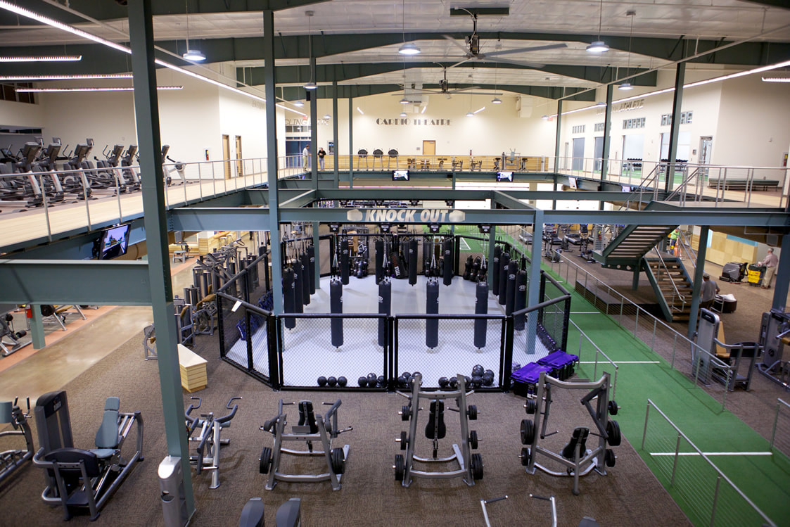 interior aerial view of open air second floor with cardio machines and track looking over enclosed boxing training area and weight machines at Evans Fitness Center