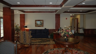 richly patterned carpets and circular wooden tables with flowers inside of lowly lit Lewis Hall at Georgia Southern University 