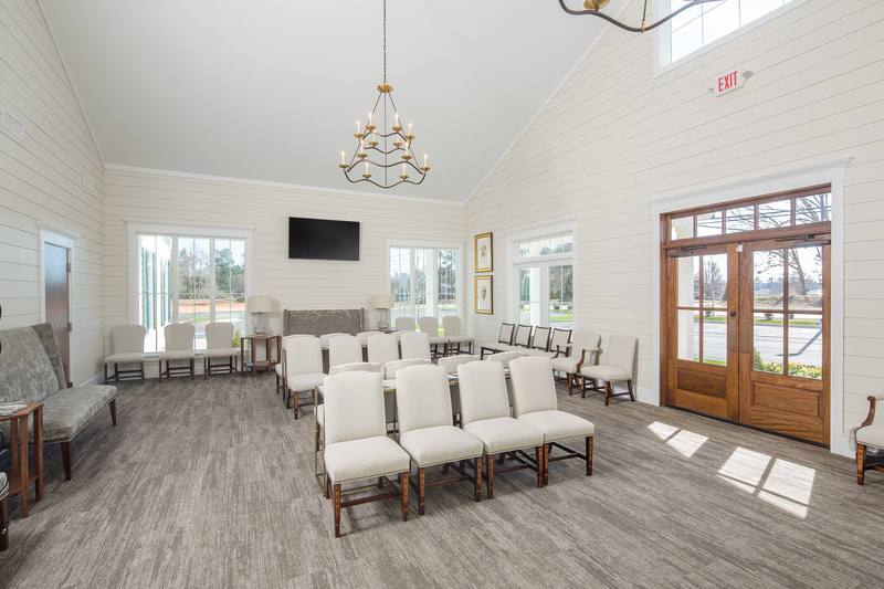 airy interior of waiting room in neutral tones with rustic chandelier and large wooden door of Savannah River Dermatology 