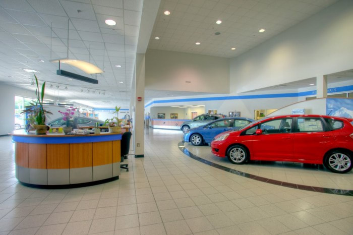 interior of Gerald Jones dealership in Augusta with red, blue, and silver cars, done in beige with bright blue accents 
