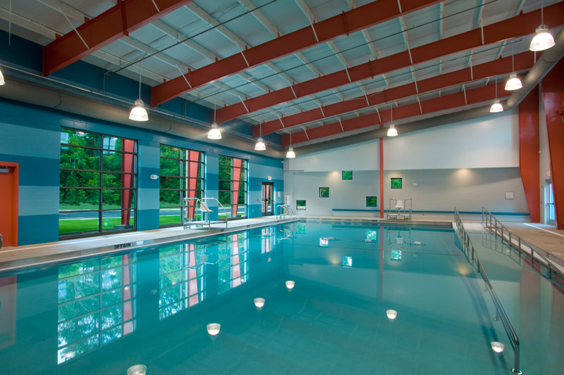 indoor pool with large open windows on teal walls and red decorative finishes at Augusta Family Y Katie's Pool 